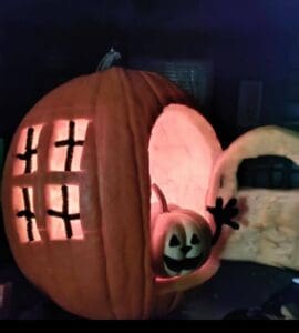 A pumpkin man in a pumpkin house waving to ask you to send your nerdy pumpkin carving ideas to Big Sea!