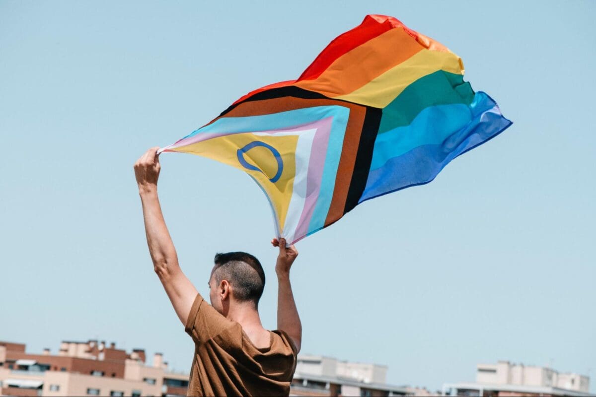 Person holding a waving pride flag above their head.