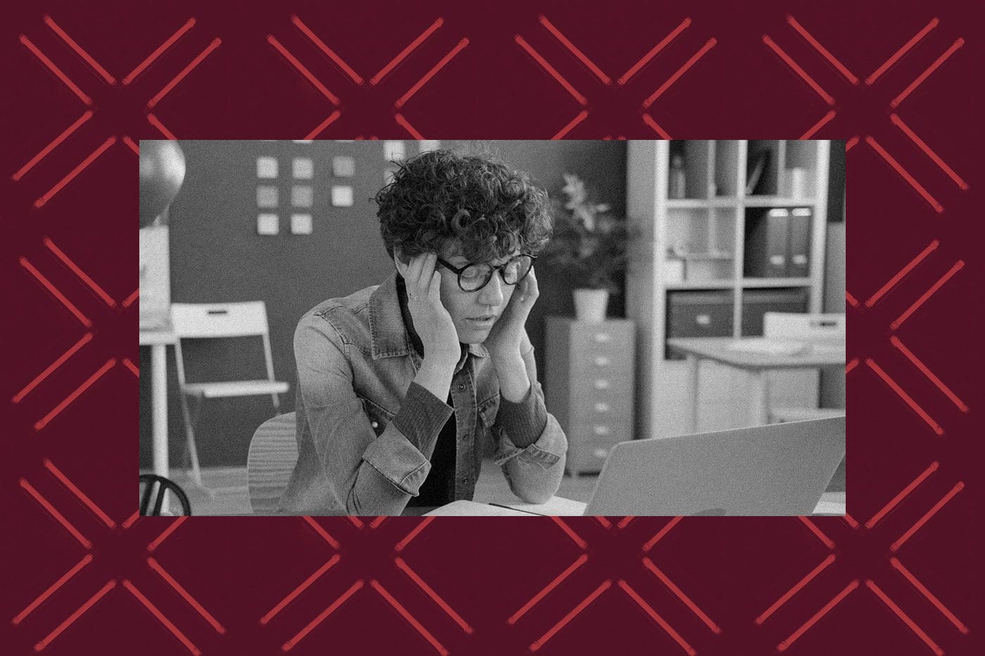 A nonprofit professional looks stressed while working on a laptop, representing the frustration of managing Google Ad Grant requirements and avoiding account suspension.