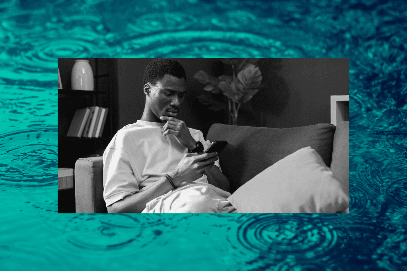 Young man sitting on a couch with a smartphone, contemplating the world events on social media that he is reading about.