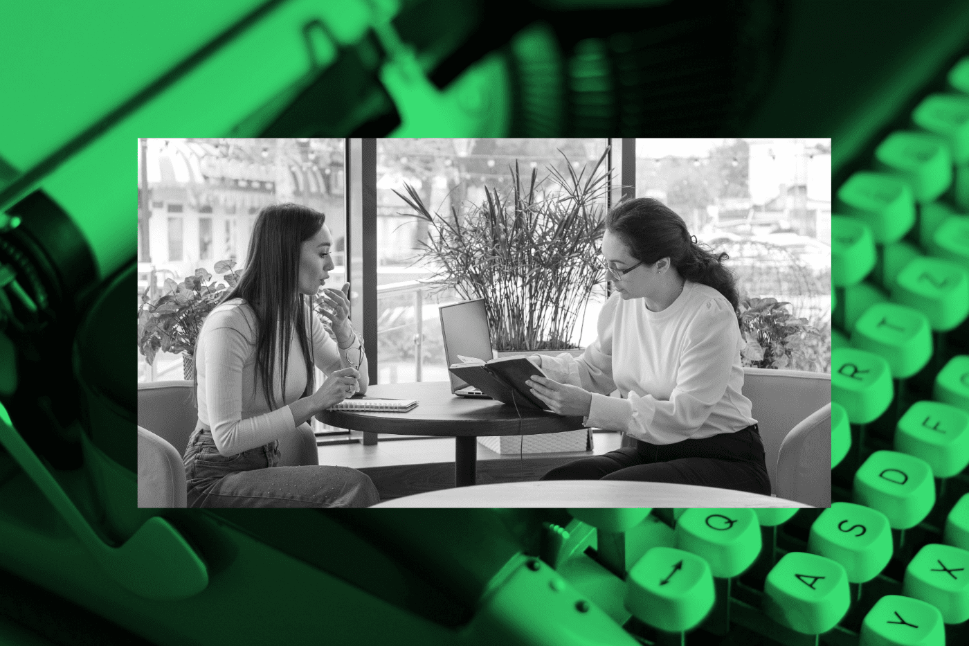 Two professionals sit in a casual office space, reviewing notes and a laptop as they talk—suggesting buyer research or persona-building.
