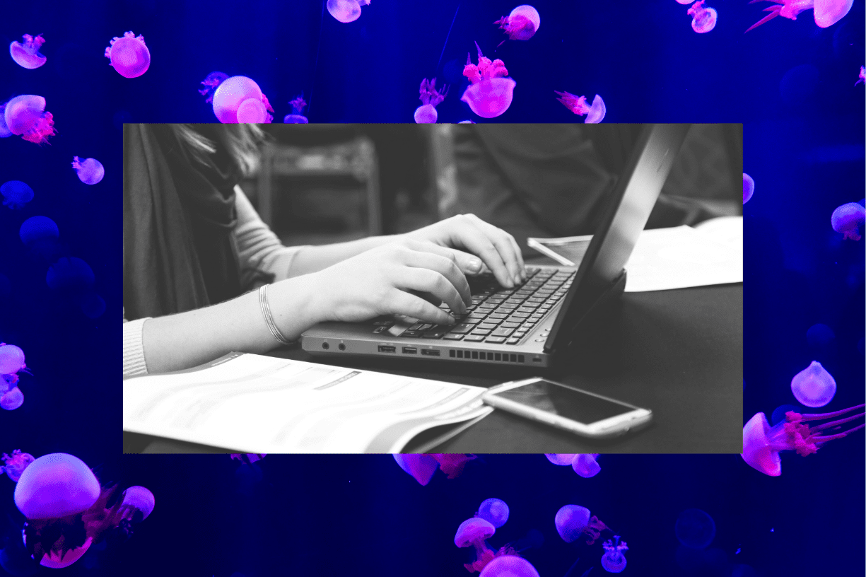 Person typing on a laptop with documents and a smartphone nearby, representing nonprofit content strategy, digital marketing planning, SEO, and storytelling in 2026.